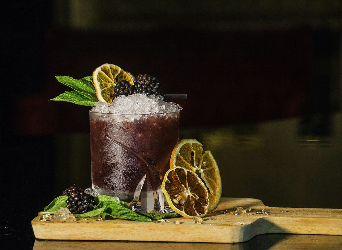 Drink scuro con more, ghiaccio tritato e lime essiccato